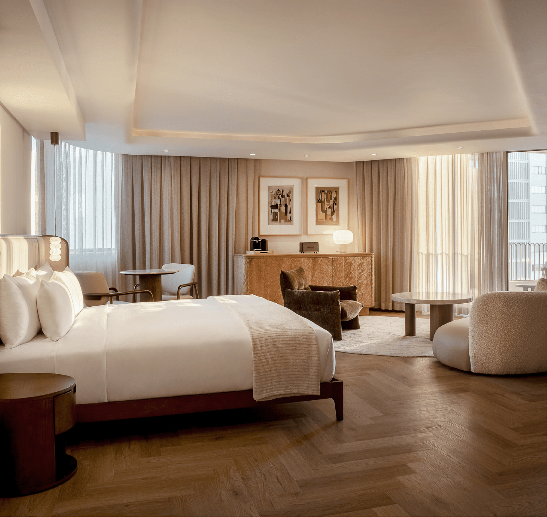 Sea-Facing Suite at The Cole with herringbone floors, velvet armchairs and a king bed dressed in white linen