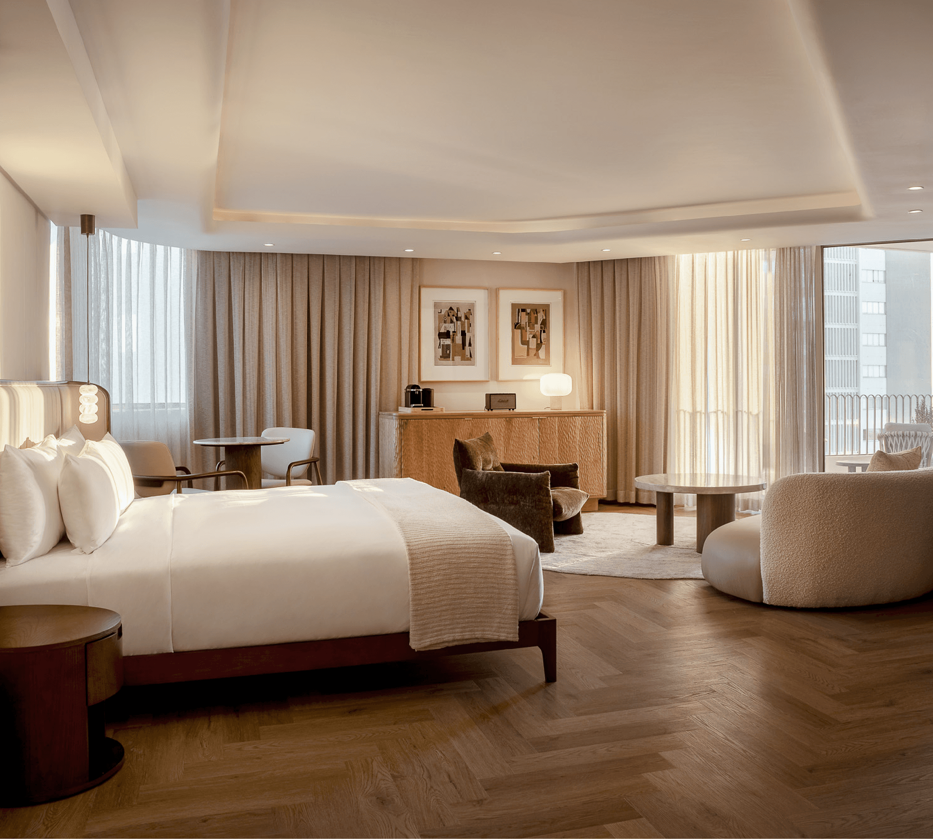 Sea-Facing Suite at The Cole with herringbone floors, velvet armchairs and a king bed dressed in white linen