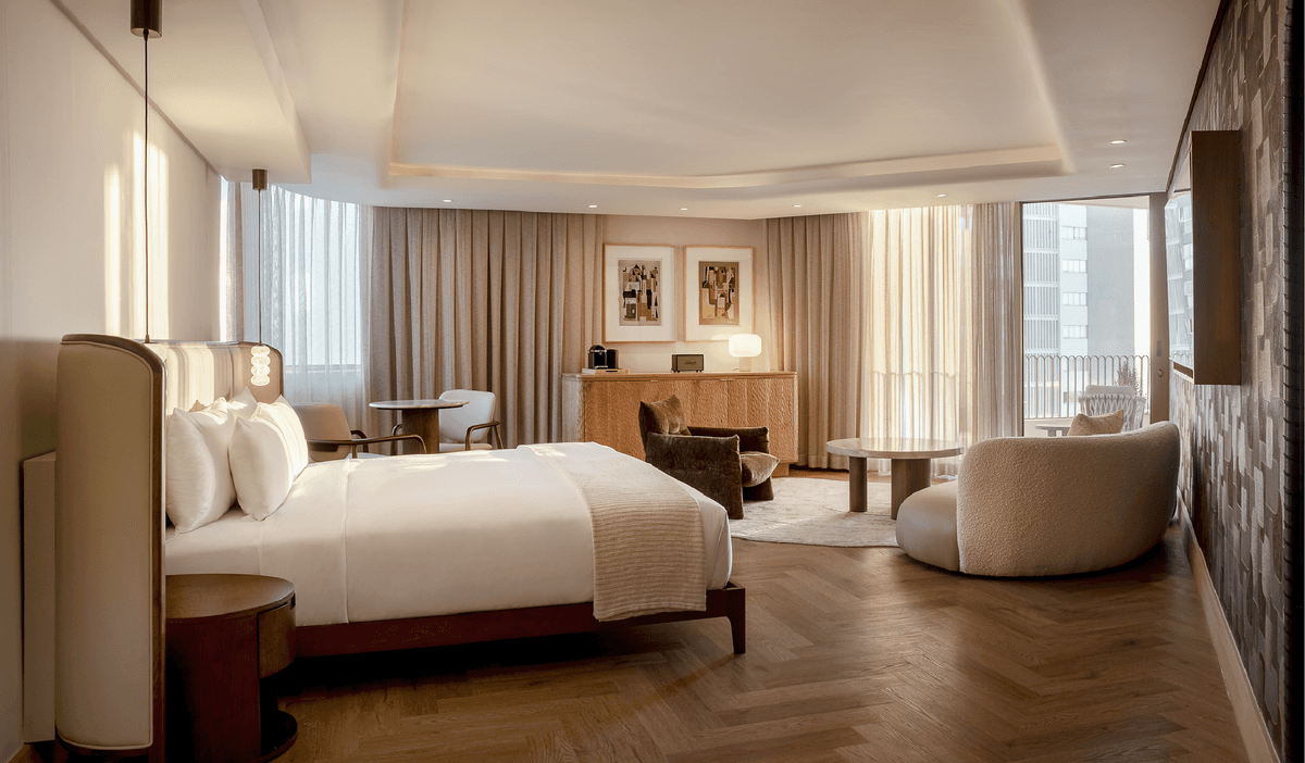 Sea-Facing Suite at The Cole with herringbone floors, velvet armchairs and a king bed dressed in white linen
